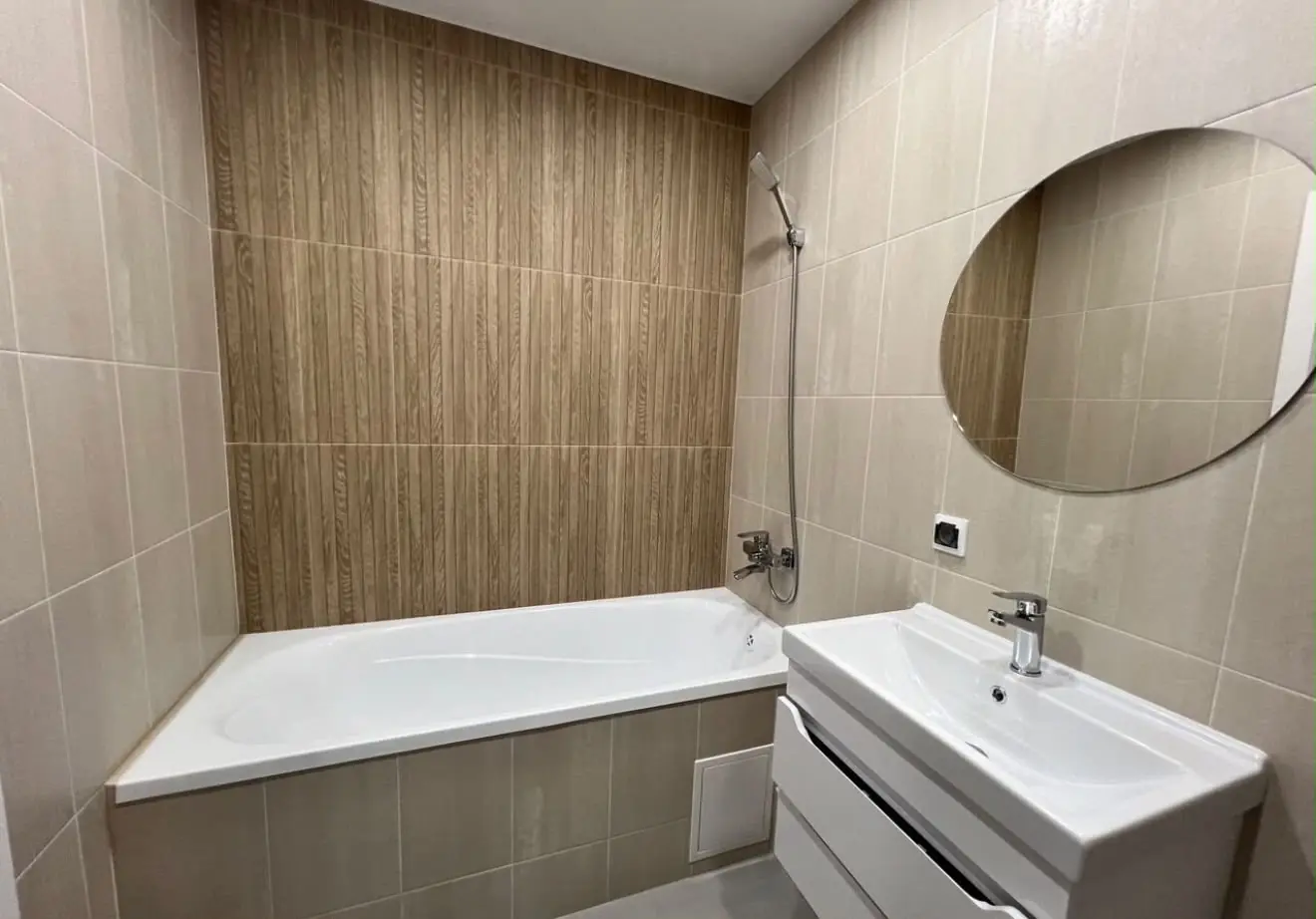 Baño beige con bañera y revestimiento efecto madera