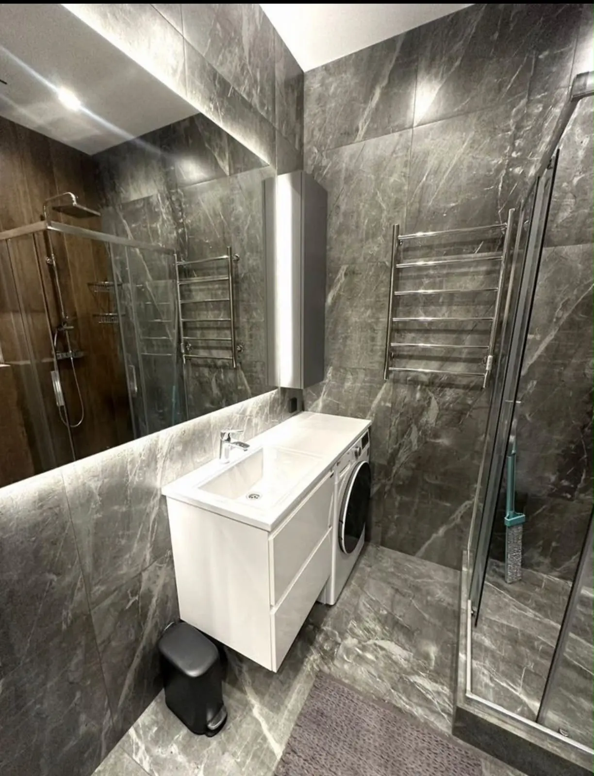 Baño gris con gran espejo retroiluminado y ducha
